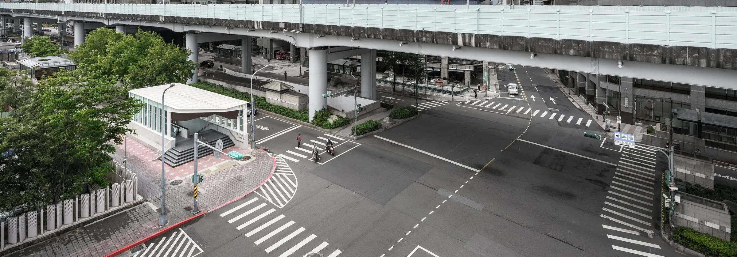 Y26 從高處看台北的路口,捷運出口的玻璃亭站在高架橋下,行人走過斑馬線